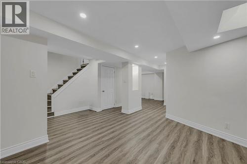 Spacious room featuring wood-finish flooring, recessed lighting, white trim, light-toned walls, and a staircase with dark treads - 191 Stirling Macgregor Drive, Cambridge, ON 