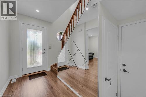 Entryway featuring wood-finish flooring, a white paneled door with decorative glass insert, and a staircase with wood banister - 191 Stirling Macgregor Drive, Cambridge, ON 