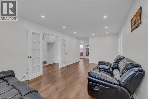Spacious room featuring wood-finish flooring, white walls, recessed lighting, and a pair of French doors - 191 Stirling Macgregor Drive, Cambridge, ON 
