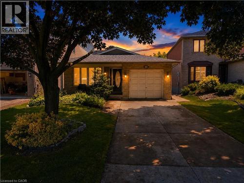 Brick facade residence featuring an attached garage with carriage-style door, a paved driveway, and established front yard landscaping - 23 Millpond Place, Mountain, ON 