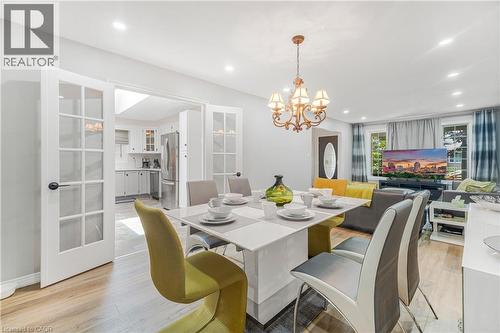 Dining area featuring wood-finish flooring, a contemporary dining table, and a bronze chandelier - 23 Millpond Place, Mountain, ON 