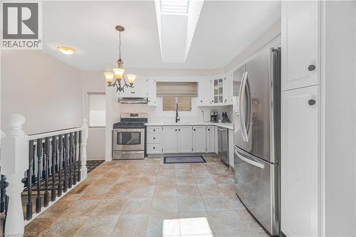 Kitchen featuring white cabinetry, stainless steel appliances, a skylight, and tiled flooring - 23 Millpond Place, Mountain, ON 