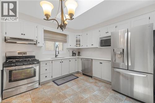 Kitchen featuring white cabinetry, stainless steel appliances, a white countertop, and tile flooring - 23 Millpond Place, Mountain, ON 