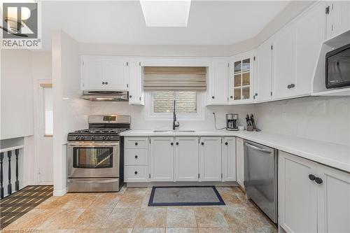 Bright kitchen featuring white cabinetry, stainless steel appliances, a tile backsplash, and light countertops - 23 Millpond Place, Mountain, ON 