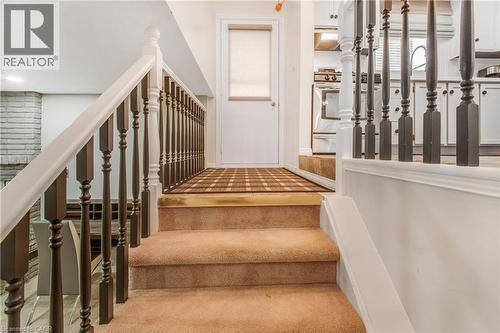 Carpeted staircase featuring a two-tone balustrade with dark wood spindles and white railings - 23 Millpond Place, Mountain, ON 