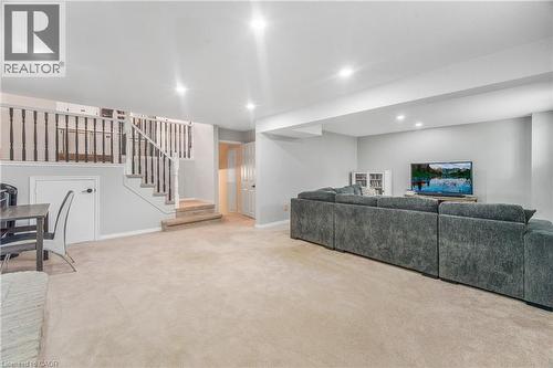 Spacious lower level featuring light-toned carpeting, recessed lighting, painted walls, a balustrade staircase, and a built-in storage area - 23 Millpond Place, Mountain, ON 