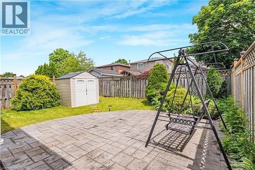 Rear yard featuring a paver patio with a swing structure, a storage shed, and mature perimeter landscaping - 23 Millpond Place, Mountain, ON 