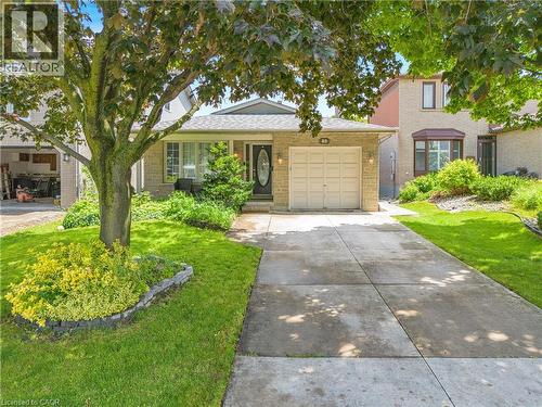 Stone veneer facade featuring a two-car garage, concrete driveway, and mature landscaping - 23 Millpond Place, Mountain, ON 