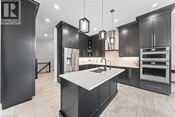 Gourmet kitchen featuring dark cabinetry, stainless steel appliances, a center island with a white countertop, recessed lighting, and tile flooring - 