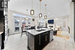 Open-concept living area featuring a kitchen island with a double sink, built-in appliances, a dining area with pendant lighting, and a living room with a fireplace - 