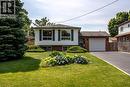 Front exterior featuring white siding with dark shutters, brick accents, an attached single-car garage, and a paved driveway - 409 Mohawk Road W, Hamilton, ON 