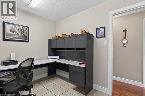 Built-in L-shaped desk with upper cabinetry, neutral wall paint, tile flooring, and white trim - 409 Mohawk Road W, Hamilton, ON 