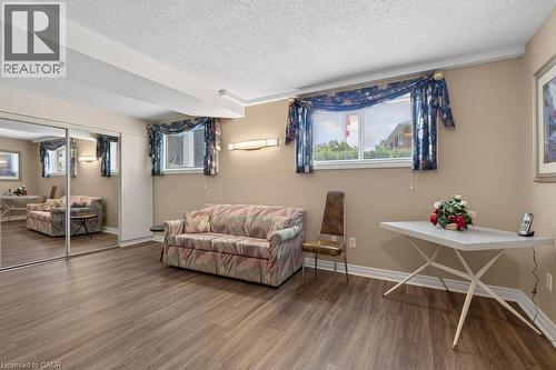 Spacious room featuring wood-finish flooring, two windows, and built-in mirrored closet doors - 409 Mohawk Road W, Hamilton, ON 