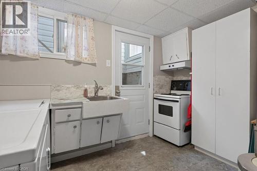 Functional utility room featuring a large basin sink, white cabinetry, and a full-size range - 409 Mohawk Road W, Hamilton, ON 