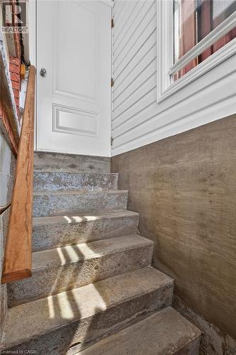 Concrete staircase with a wooden handrail, leading to a white paneled door - 409 Mohawk Road W, Hamilton, ON 