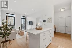 Modern kitchen island with a light-toned countertop and ample storage, complemented by light wood-finish flooring - 