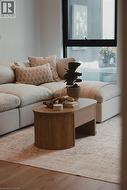 Spacious living area featuring expansive windows, wood-finish flooring, and light-toned walls - 