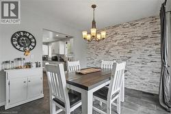 Dining area featuring a stone-clad accent wall, dark tile flooring, and a bronze chandelier with frosted glass shades - 