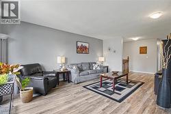 Spacious living area featuring wood-finish flooring, a neutral color palette, and flush-mount ceiling lighting - 