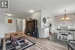 Living and dining areas featuring wood-finish flooring, a stone-accent wall, and recessed lighting - 