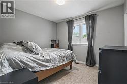 Carpeted room with light grey walls and a single window featuring white blinds and dark grey drapes - 