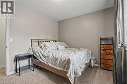 Bedroom featuring neutral wall paint, textured carpeting, and a window with blinds - 