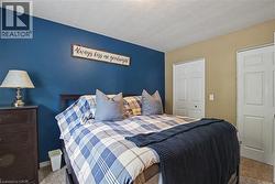 Bedroom featuring a deep blue accent wall, neutral carpeting, and two paneled closet doors - 