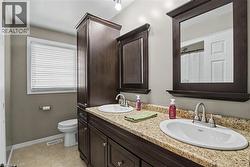 Double vanity with dark wood-finish cabinetry and framed mirrors, featuring dual undermount sinks and a speckled countertop - 