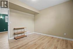 Spacious room with light wood-finish flooring, neutral wall paint, and white baseboards - 