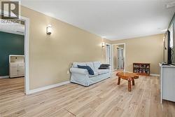 Spacious room featuring wood-finish flooring, neutral-toned walls, and recessed wall sconces - 