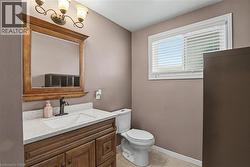 Bathroom featuring a wood-finish vanity with a light speckled countertop and integrated sink, a dark bronze faucet, and a large framed mirror - 