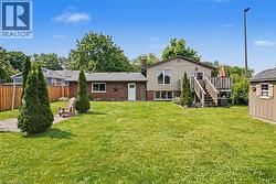 Spacious backyard featuring a wood deck with stairs, a storage shed, and a gravel path - 