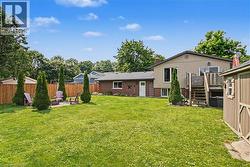 Expansive backyard featuring a manicured lawn, a privacy fence, and mature trees - 
