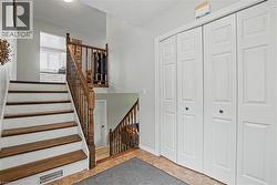 Split-level entry featuring wood-finish stair treads with white risers and a matching wood-finish banister - 