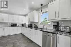 Modern kitchen featuring white shaker cabinetry, dark patterned countertops, a stainless steel dishwasher, white subway tile backsplash, and dark tile flooring - 
