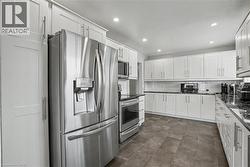 Sleek kitchen featuring stainless steel appliances, extensive white cabinetry, dark stone countertops, subway tile backsplash, and recessed lighting - 