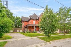 Brick exterior with a prominent front porch, gabled roofline, and mature trees - 