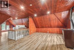 Expansive upper-level space featuring rich wood-paneled walls and ceiling, recessed lighting, and light wood-finish flooring - 