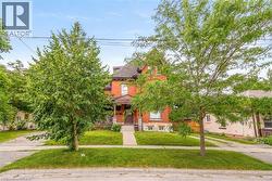Brick residence featuring a covered front porch, gabled roofline, and mature front yard trees - 