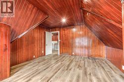 Room with wood-finish flooring, vertical wood paneling, and a sloped wood-paneled ceiling - 
