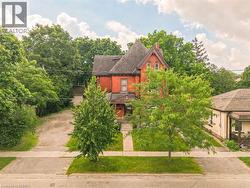 Red brick residence featuring a prominent turret, front porch, and mature trees - 