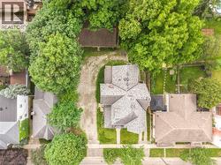 Property featuring a shingle roof, a gravel driveway, and surrounding mature trees - 