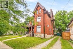Brick multi-story residence featuring arched windows and a covered front porch - 