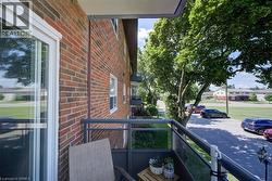 Private balcony with glass and metal railing, featuring a brick exterior facade and a sliding glass door - 