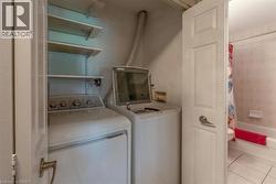 Dedicated laundry area featuring a washer and dryer, adjacent to a full bathroom with a tiled shower/tub combination and tiled flooring - 