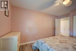 Bedroom featuring wood-finish flooring, a ceiling fan with integrated lighting, and white bi-fold closet doors - 