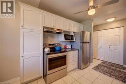 Kitchen featuring white cabinetry, stainless steel appliances, a built-in microwave, and tile flooring - 