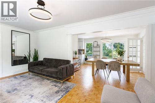Open-concept living space featuring wood-finish parquet flooring, white crown molding, and recessed lighting - 176 Riverbank Drive, Cambridge, ON 