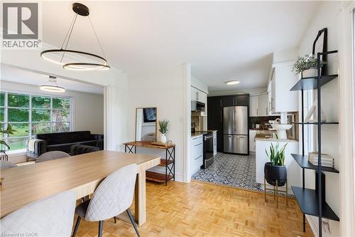 Open-concept dining area featuring wood-finish parquet flooring and modern circular pendant lighting - 176 Riverbank Drive, Cambridge, ON 