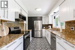 Kitchen with patterned floor tiles, white cabinetry, and stainless steel appliances - 